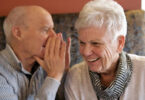 Elderly man whispers into a elderly womans ear